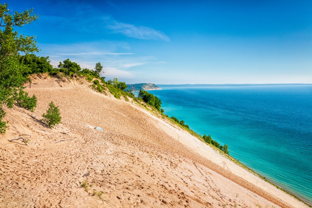 A large sand dune above a lake.