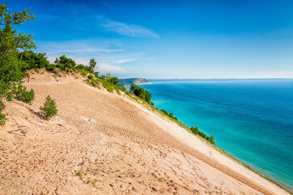 A large sand dune above a lake.